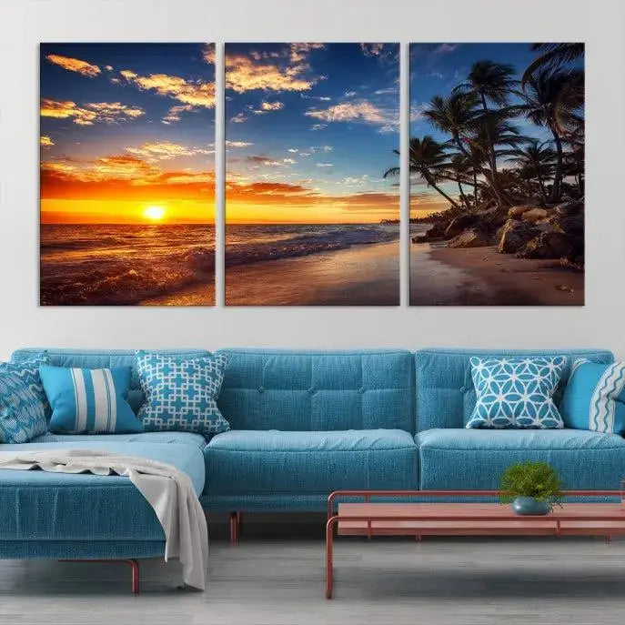 A Coastal Wall Art Beach at Sunset Canvas Print, featuring a triptych of a tropical sunset over the ocean with palm trees, graces the room.