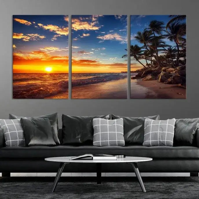 A Coastal Wall Art Beach at Sunset Canvas Print, featuring a triptych of a tropical sunset over the ocean with palm trees, graces the room.