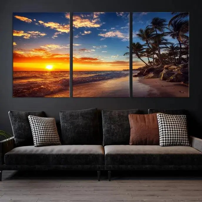 A Coastal Wall Art Beach at Sunset Canvas Print, featuring a triptych of a tropical sunset over the ocean with palm trees, graces the room.