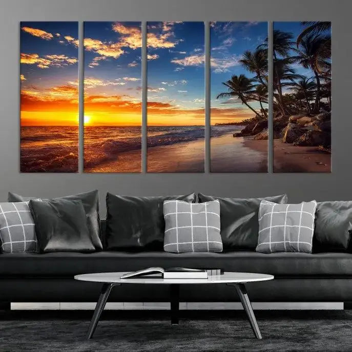 A Coastal Wall Art Beach at Sunset Canvas Print, featuring a triptych of a tropical sunset over the ocean with palm trees, graces the room.