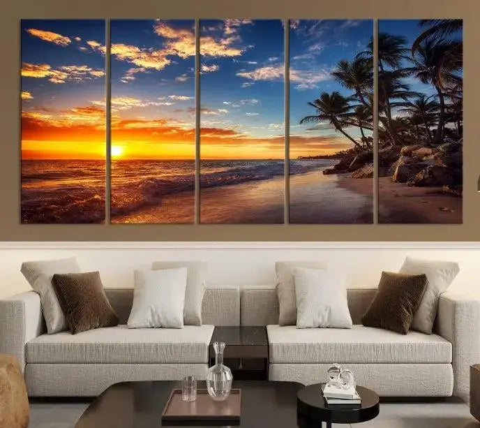 A Coastal Wall Art Beach at Sunset Canvas Print, featuring a triptych of a tropical sunset over the ocean with palm trees, graces the room.