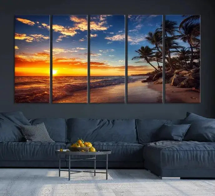 A Coastal Wall Art Beach at Sunset Canvas Print, featuring a triptych of a tropical sunset over the ocean with palm trees, graces the room.