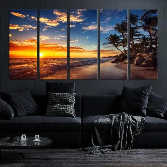 A Coastal Wall Art Beach at Sunset Canvas Print, featuring a triptych of a tropical sunset over the ocean with palm trees, graces the room.