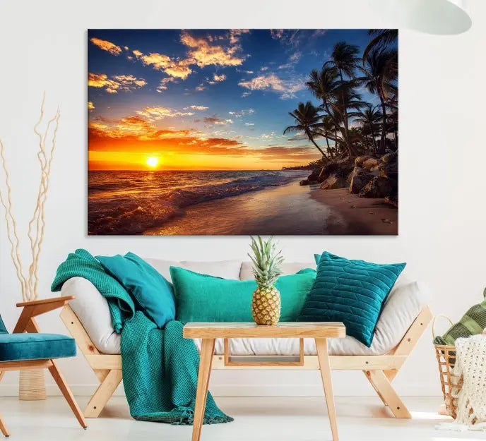 A Coastal Wall Art Beach at Sunset Canvas Print, featuring a triptych of a tropical sunset over the ocean with palm trees, graces the room.