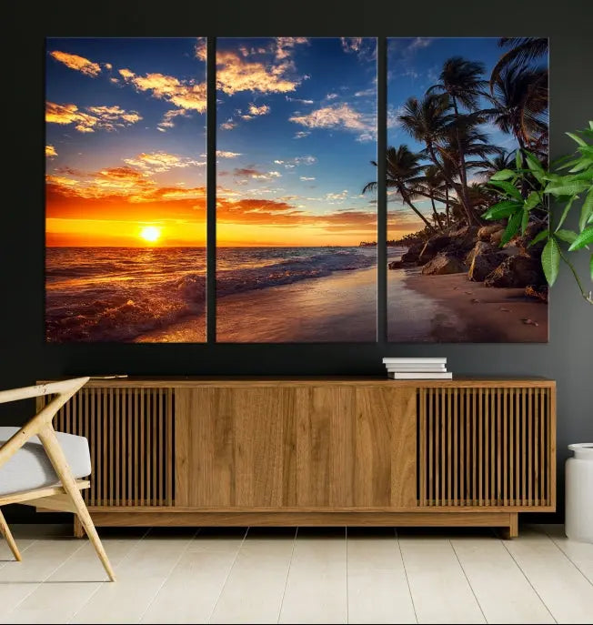 A Coastal Wall Art Beach at Sunset Canvas Print, featuring a triptych of a tropical sunset over the ocean with palm trees, graces the room.