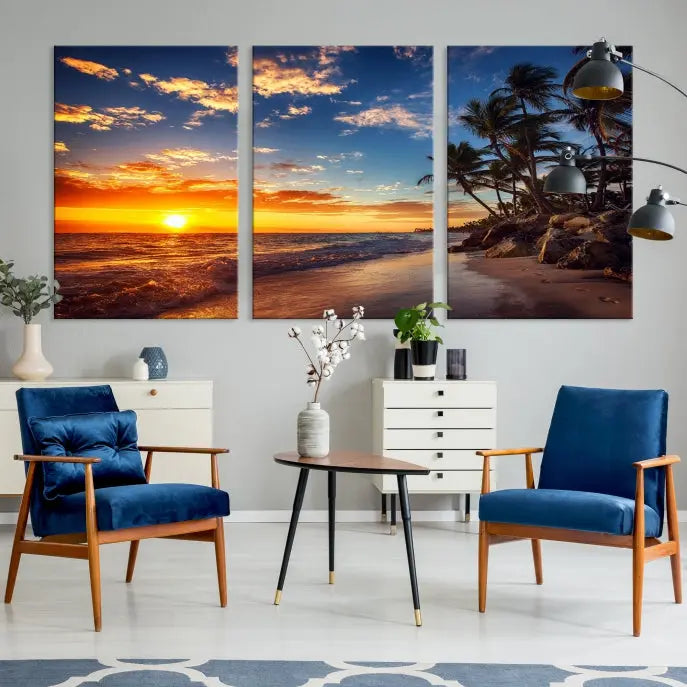 A Coastal Wall Art Beach at Sunset Canvas Print, featuring a triptych of a tropical sunset over the ocean with palm trees, graces the room.