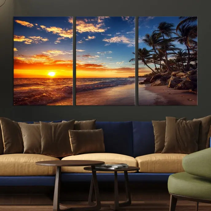 A Coastal Wall Art Beach at Sunset Canvas Print, featuring a triptych of a tropical sunset over the ocean with palm trees, graces the room.