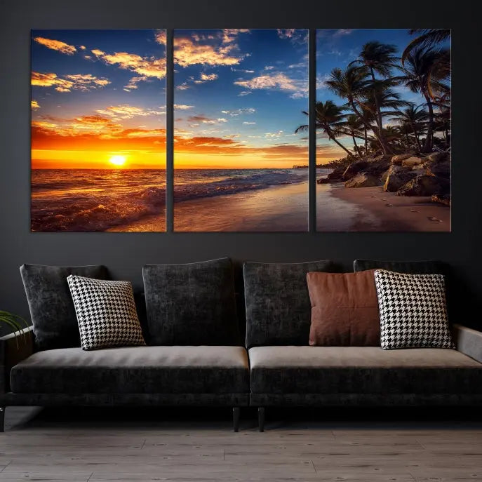 A Coastal Wall Art Beach at Sunset Canvas Print, featuring a triptych of a tropical sunset over the ocean with palm trees, graces the room.