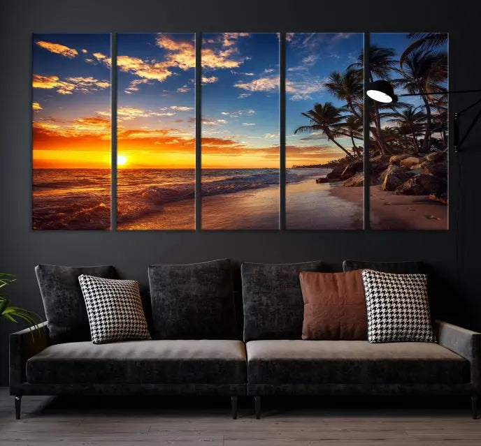 A Coastal Wall Art Beach at Sunset Canvas Print, featuring a triptych of a tropical sunset over the ocean with palm trees, graces the room.