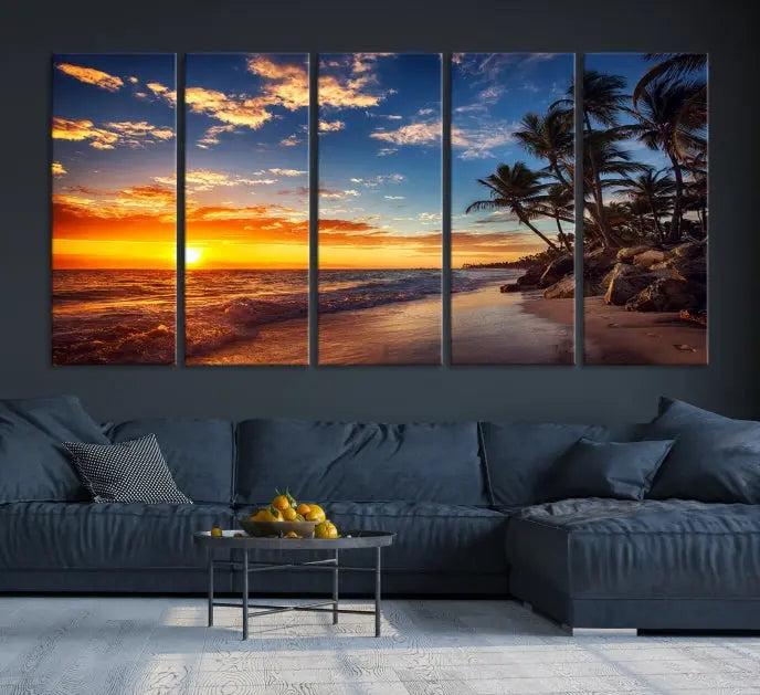 A Coastal Wall Art Beach at Sunset Canvas Print, featuring a triptych of a tropical sunset over the ocean with palm trees, graces the room.