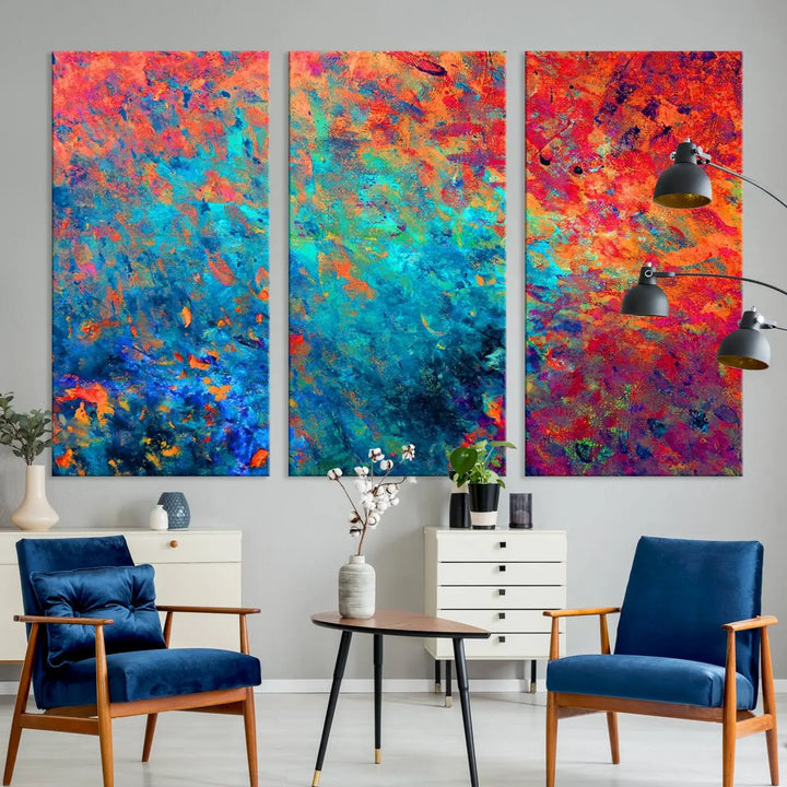 A three-part Colorful Abstract Canvas Wall Art Print, featuring vivid splashes of blue, orange, and red, is showcased on gallery-wrapped, museum-quality canvas with a UV-protective coating.