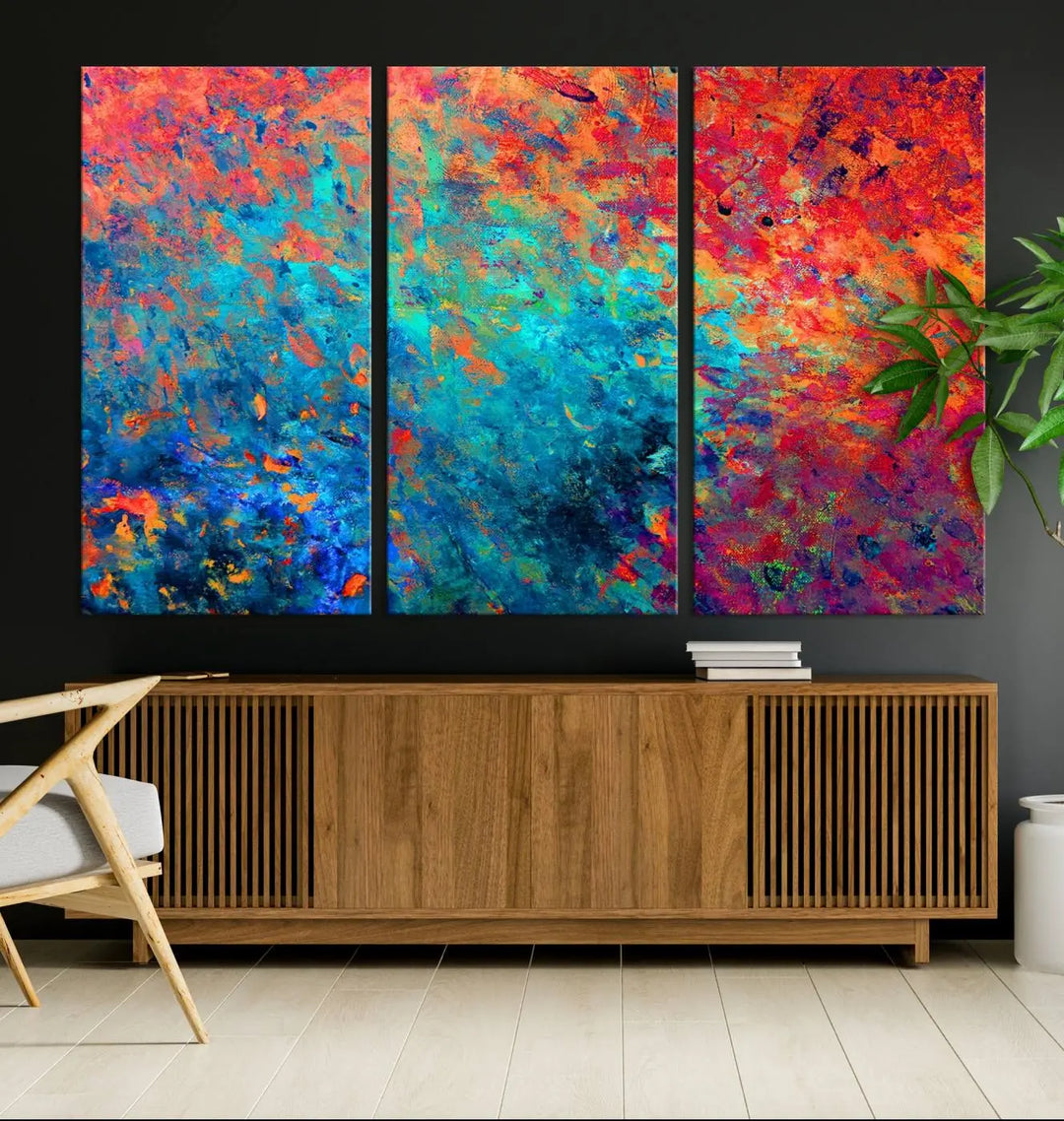 A three-part Colorful Abstract Canvas Wall Art Print, featuring vivid splashes of blue, orange, and red, is showcased on gallery-wrapped, museum-quality canvas with a UV-protective coating.