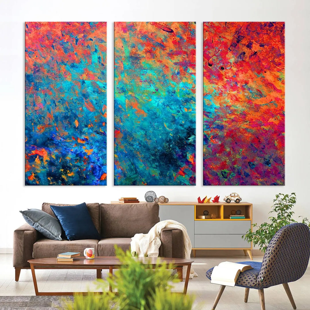 A three-part Colorful Abstract Canvas Wall Art Print, featuring vivid splashes of blue, orange, and red, is showcased on gallery-wrapped, museum-quality canvas with a UV-protective coating.