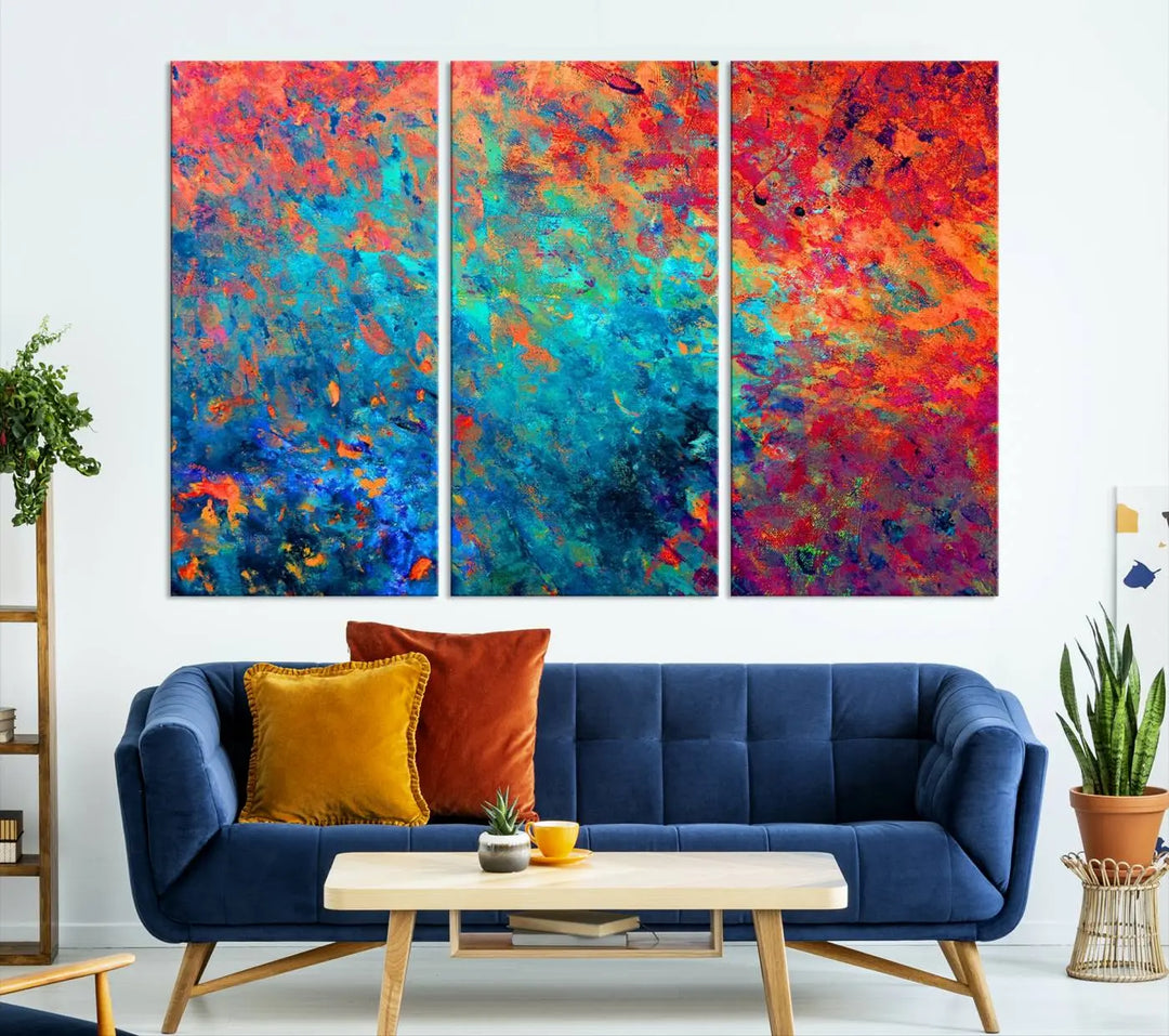 A three-part Colorful Abstract Canvas Wall Art Print, featuring vivid splashes of blue, orange, and red, is showcased on gallery-wrapped, museum-quality canvas with a UV-protective coating.