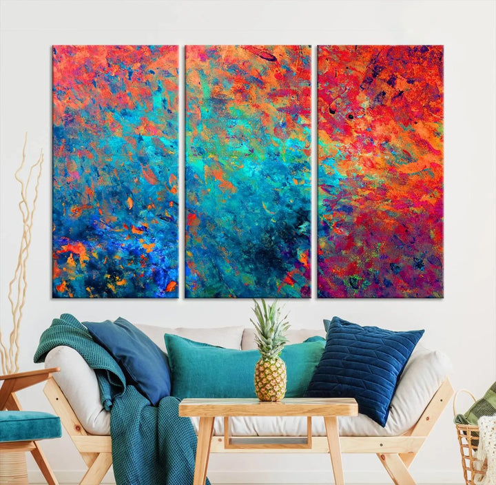 A three-part Colorful Abstract Canvas Wall Art Print, featuring vivid splashes of blue, orange, and red, is showcased on gallery-wrapped, museum-quality canvas with a UV-protective coating.