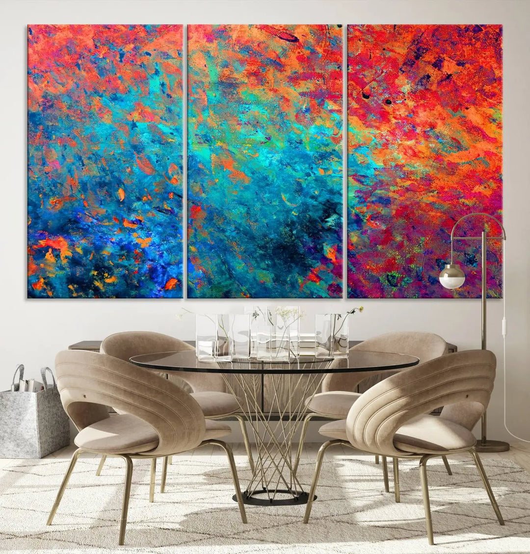 A three-part Colorful Abstract Canvas Wall Art Print, featuring vivid splashes of blue, orange, and red, is showcased on gallery-wrapped, museum-quality canvas with a UV-protective coating.