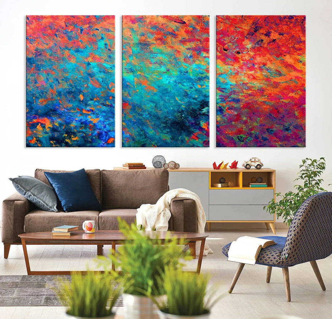 A three-part Colorful Abstract Canvas Wall Art Print, featuring vivid splashes of blue, orange, and red, is showcased on gallery-wrapped, museum-quality canvas with a UV-protective coating.