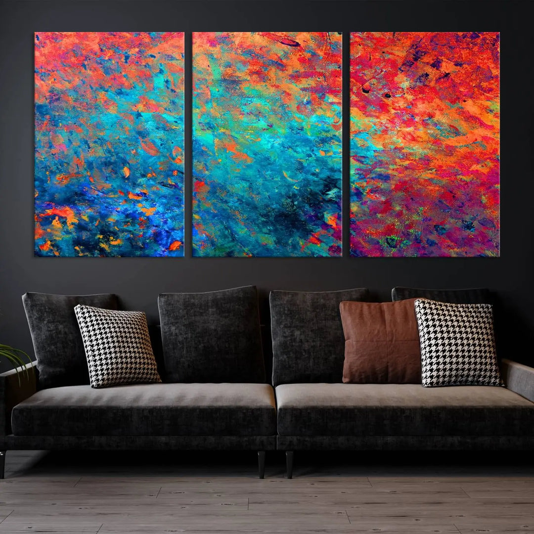 A three-part Colorful Abstract Canvas Wall Art Print, featuring vivid splashes of blue, orange, and red, is showcased on gallery-wrapped, museum-quality canvas with a UV-protective coating.