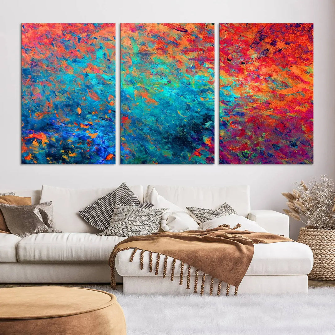 A three-part Colorful Abstract Canvas Wall Art Print, featuring vivid splashes of blue, orange, and red, is showcased on gallery-wrapped, museum-quality canvas with a UV-protective coating.