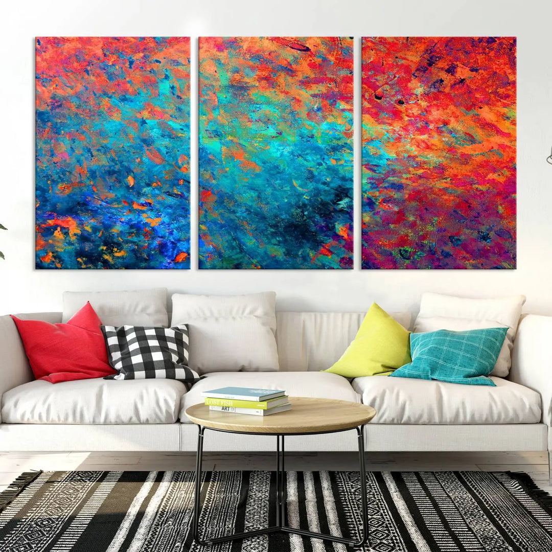 A three-part Colorful Abstract Canvas Wall Art Print, featuring vivid splashes of blue, orange, and red, is showcased on gallery-wrapped, museum-quality canvas with a UV-protective coating.