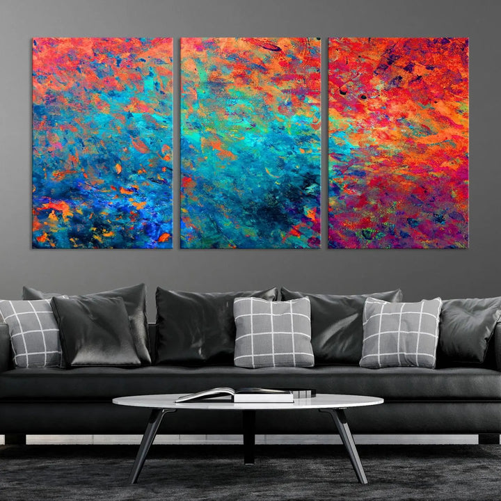 A three-part Colorful Abstract Canvas Wall Art Print, featuring vivid splashes of blue, orange, and red, is showcased on gallery-wrapped, museum-quality canvas with a UV-protective coating.