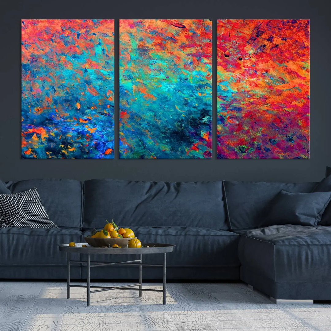 A three-part Colorful Abstract Canvas Wall Art Print, featuring vivid splashes of blue, orange, and red, is showcased on gallery-wrapped, museum-quality canvas with a UV-protective coating.