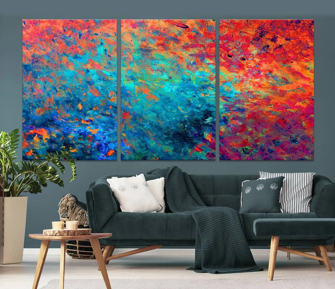 A three-part Colorful Abstract Canvas Wall Art Print, featuring vivid splashes of blue, orange, and red, is showcased on gallery-wrapped, museum-quality canvas with a UV-protective coating.