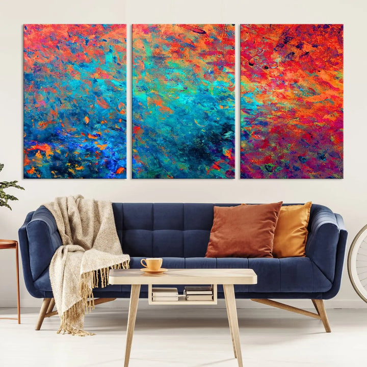 A three-part Colorful Abstract Canvas Wall Art Print, featuring vivid splashes of blue, orange, and red, is showcased on gallery-wrapped, museum-quality canvas with a UV-protective coating.