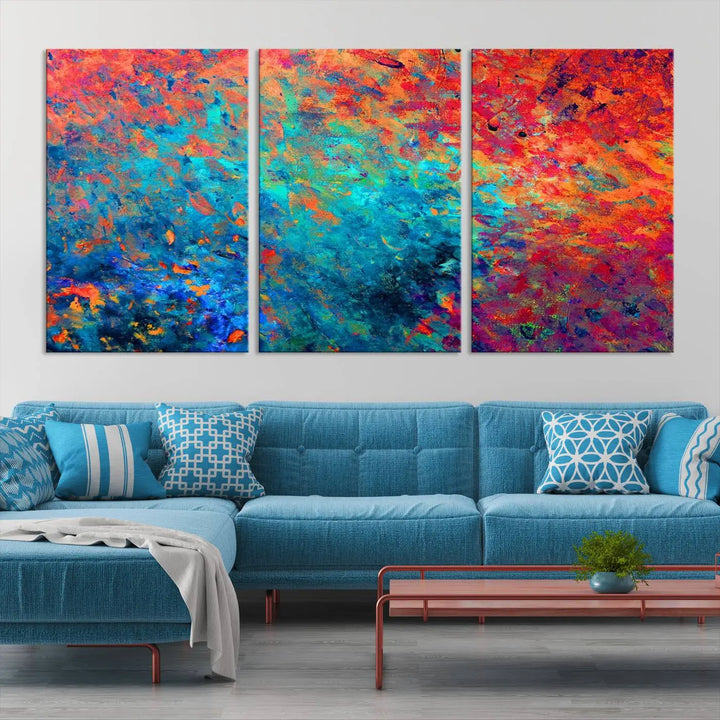 A three-part Colorful Abstract Canvas Wall Art Print, featuring vivid splashes of blue, orange, and red, is showcased on gallery-wrapped, museum-quality canvas with a UV-protective coating.