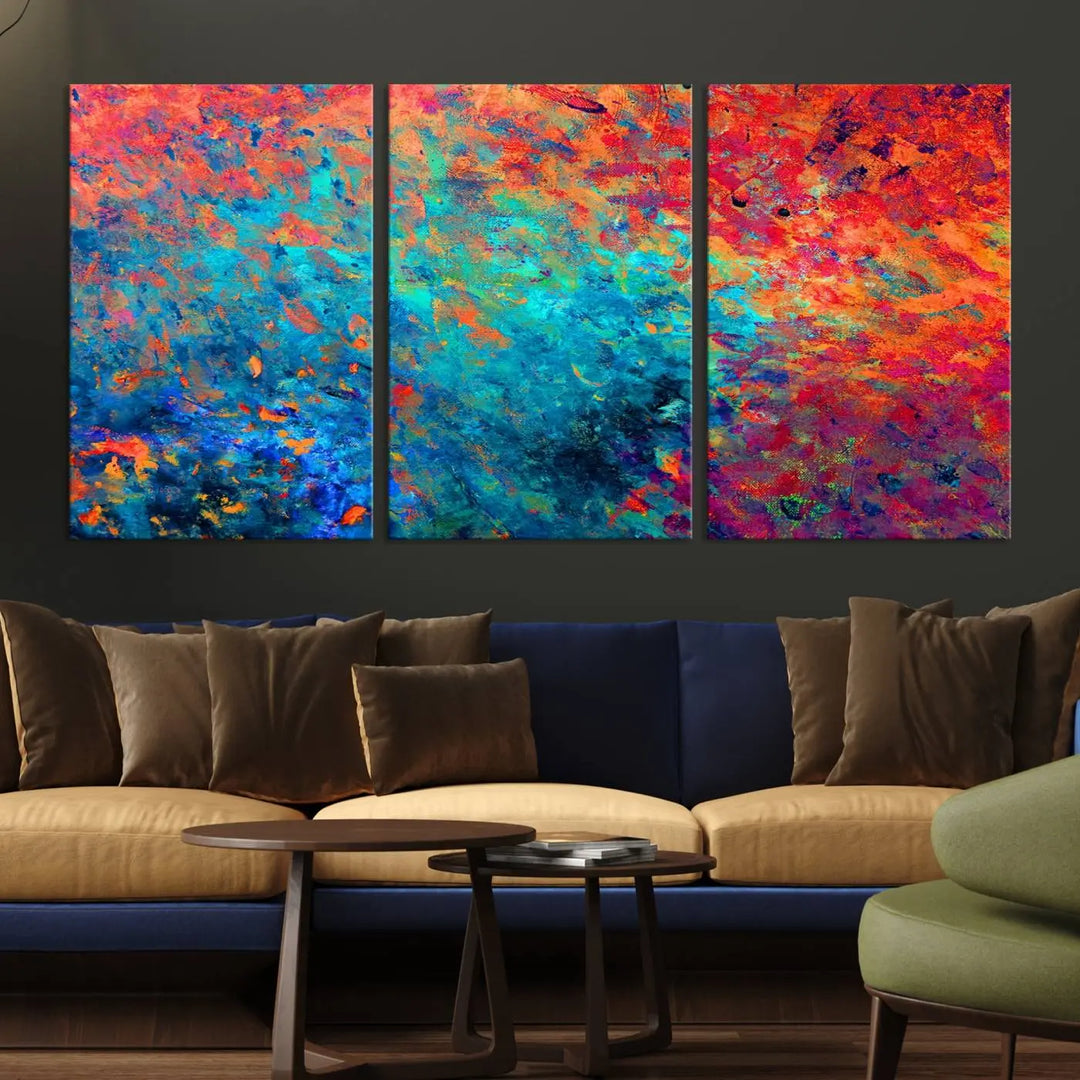 A three-part Colorful Abstract Canvas Wall Art Print, featuring vivid splashes of blue, orange, and red, is showcased on gallery-wrapped, museum-quality canvas with a UV-protective coating.