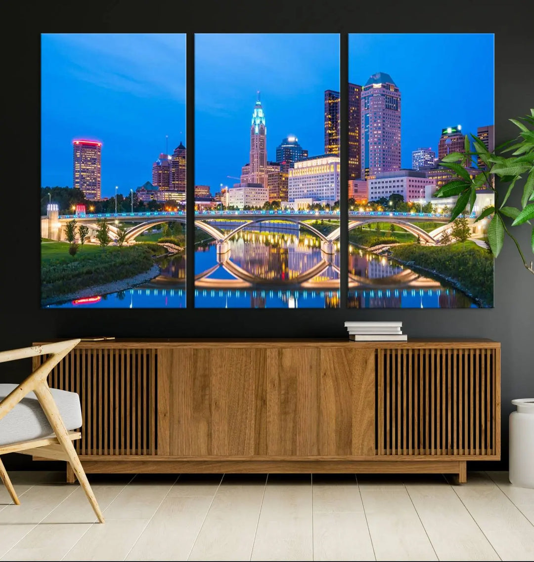 The modern living room is enhanced by the striking Columbus City Lights Bright Blue Skyline Cityscape View Wall Art Canvas Print displayed above white cabinets. This piece is crafted on museum-quality canvas with a UV-protective coating to ensure lasting beauty and vibrant colors.