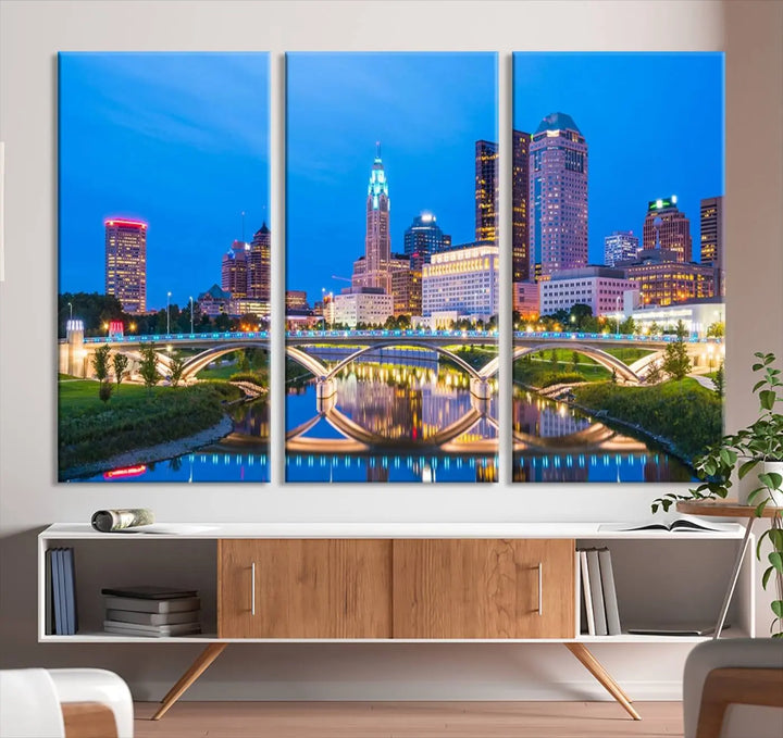 The modern living room is enhanced by the striking Columbus City Lights Bright Blue Skyline Cityscape View Wall Art Canvas Print displayed above white cabinets. This piece is crafted on museum-quality canvas with a UV-protective coating to ensure lasting beauty and vibrant colors.