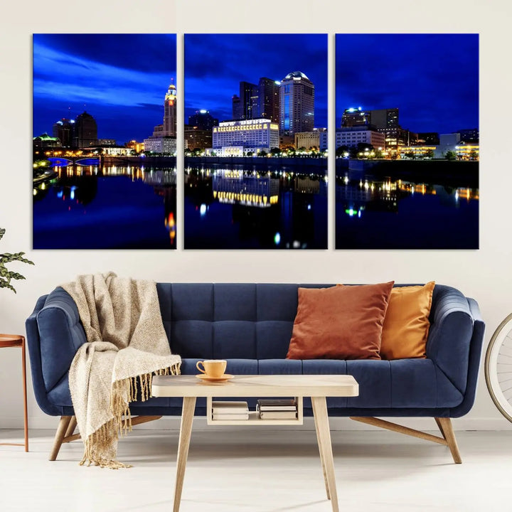 The living room showcases the Columbus City Lights Night Bright Blue Skyline Cityscape View Wall Art Canvas Print on a museum-quality canvas. The professionally hand-assembled artwork adds elegance while ensuring durable beauty.