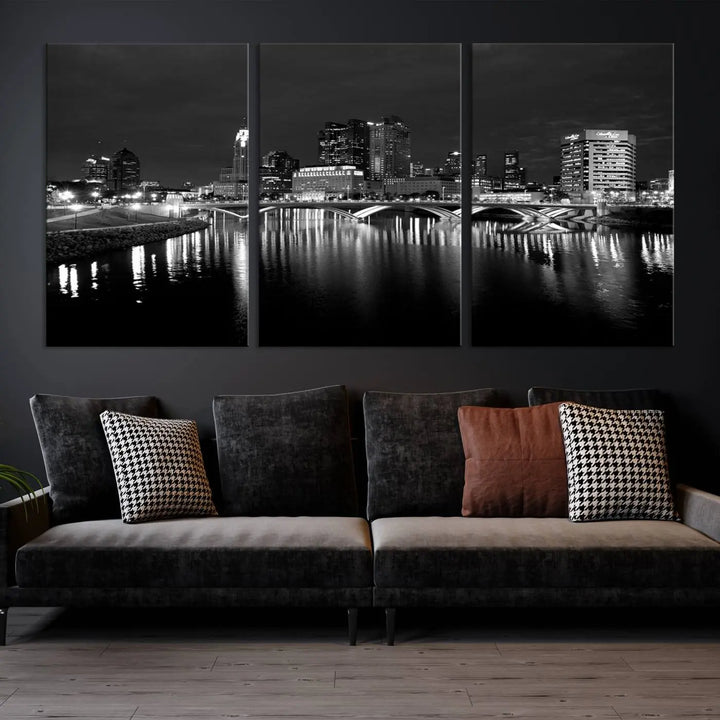 In a modern living room, the Columbus City Lights Skyline Black and White Wall Art cityscape canvas print elegantly adorns the wall above the couch. Its UV-protective coating ensures lasting elegance, and you can enjoy free shipping on this stylish centerpiece.