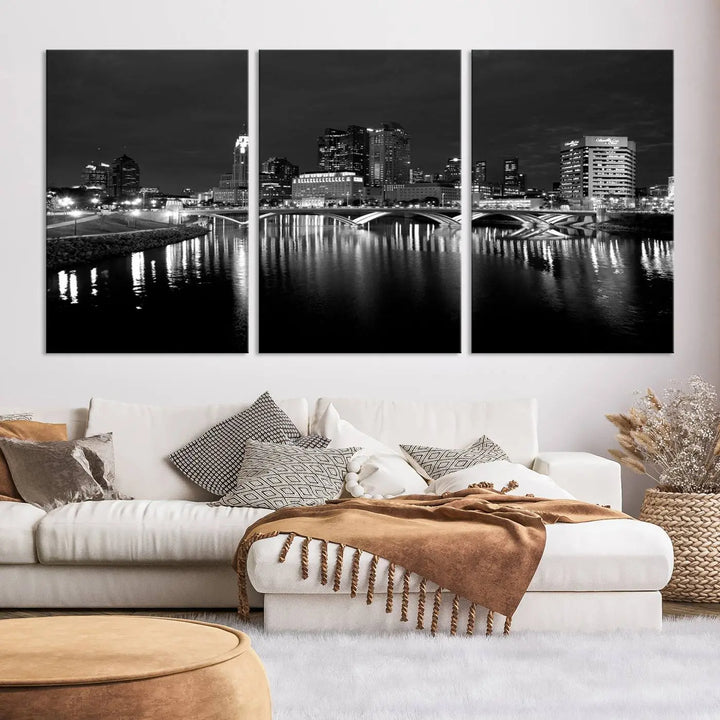 In a modern living room, the Columbus City Lights Skyline Black and White Wall Art cityscape canvas print elegantly adorns the wall above the couch. Its UV-protective coating ensures lasting elegance, and you can enjoy free shipping on this stylish centerpiece.