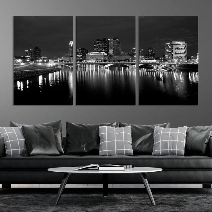 In a modern living room, the Columbus City Lights Skyline Black and White Wall Art cityscape canvas print elegantly adorns the wall above the couch. Its UV-protective coating ensures lasting elegance, and you can enjoy free shipping on this stylish centerpiece.