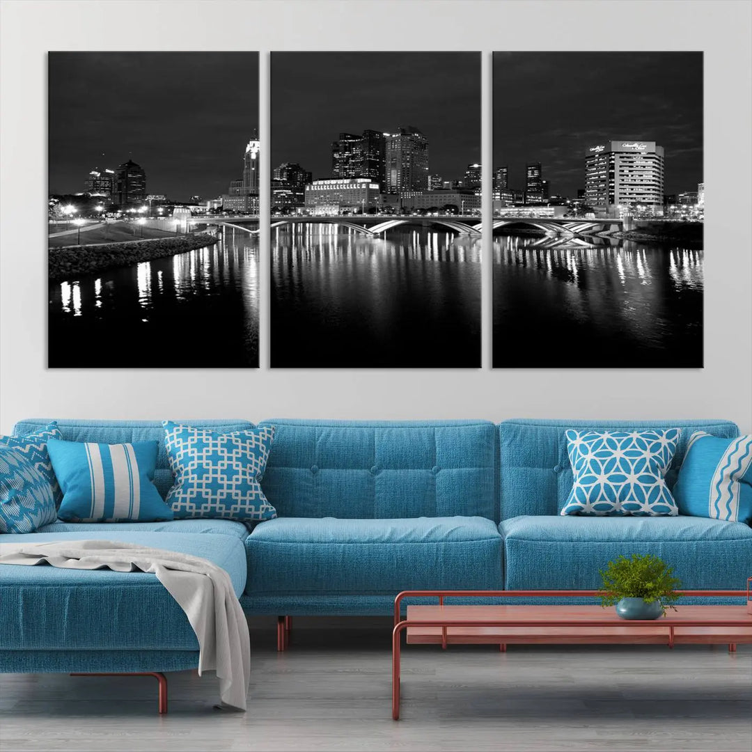 In a modern living room, the Columbus City Lights Skyline Black and White Wall Art cityscape canvas print elegantly adorns the wall above the couch. Its UV-protective coating ensures lasting elegance, and you can enjoy free shipping on this stylish centerpiece.