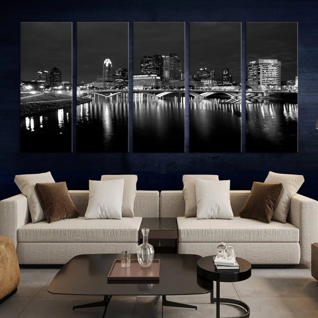 In a modern living room, the Columbus City Lights Skyline Black and White Wall Art cityscape canvas print elegantly adorns the wall above the couch. Its UV-protective coating ensures lasting elegance, and you can enjoy free shipping on this stylish centerpiece.