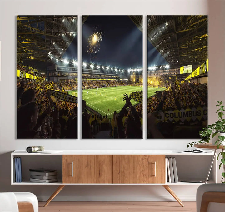 The wall of a modern living room is adorned with a triptych canvas titled "Columbus Crew Soccer Team Print," capturing the vibrant energy of the Columbus Crew Stadium in high-resolution printing.