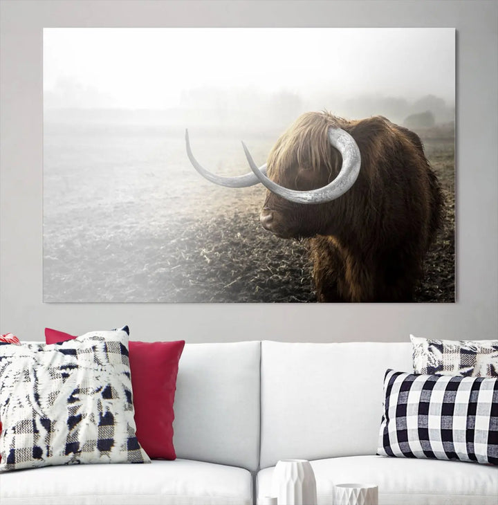 A captivating Cow Wall Art Canvas Print featuring a Highland cow with impressive horns in a misty field, crafted on museum-quality canvas. Its UV-protective coating preserves the artwork's vibrant colors.