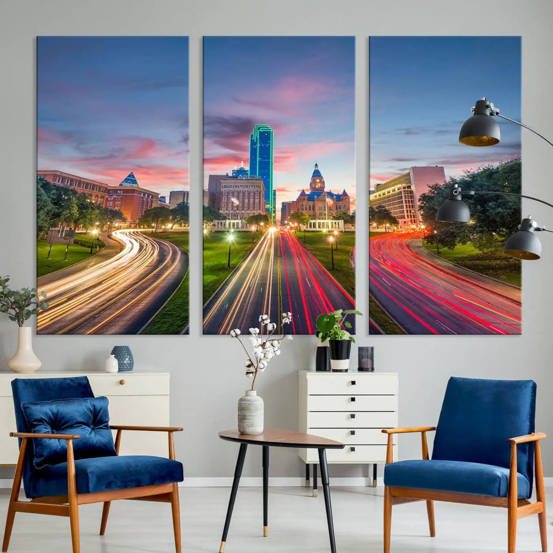 A modern living room features a cityscape triptych wall art titled "Dallas City Street Lights Sunset Pink Cloudy Skyline Cityscape View," printed on museum-quality canvas. It captures a vibrant evening skyline with light trails.