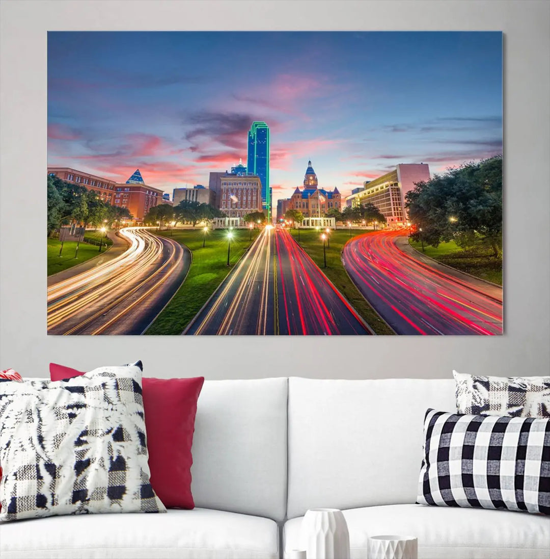 A modern living room features a cityscape triptych wall art titled "Dallas City Street Lights Sunset Pink Cloudy Skyline Cityscape View," printed on museum-quality canvas. It captures a vibrant evening skyline with light trails.