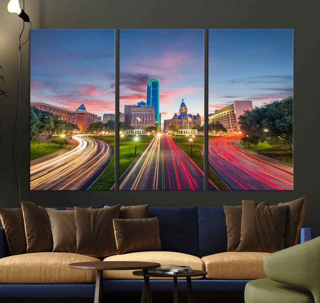 A modern living room features a cityscape triptych wall art titled "Dallas City Street Lights Sunset Pink Cloudy Skyline Cityscape View," printed on museum-quality canvas. It captures a vibrant evening skyline with light trails.