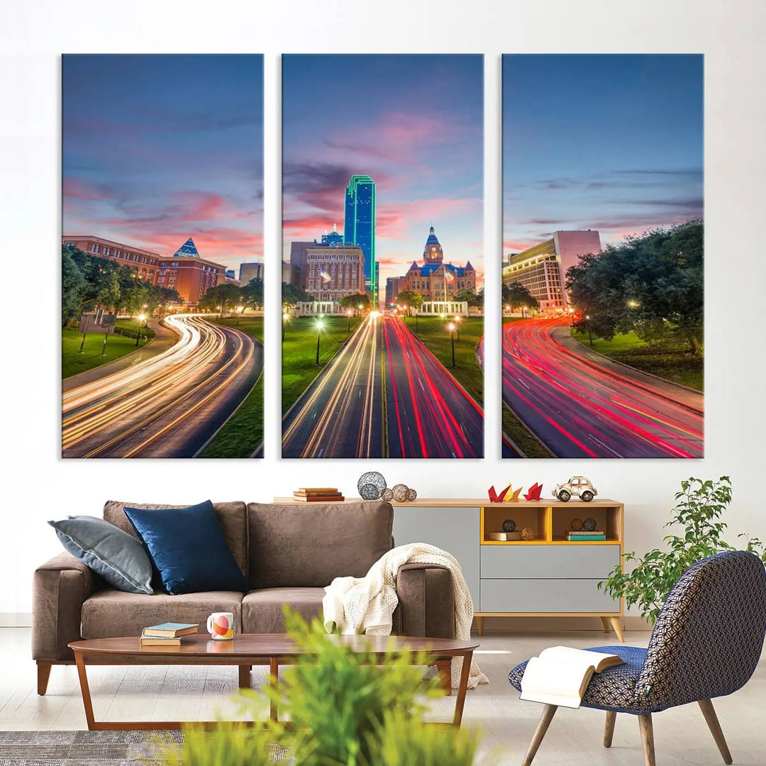 A modern living room features a cityscape triptych wall art titled "Dallas City Street Lights Sunset Pink Cloudy Skyline Cityscape View," printed on museum-quality canvas. It captures a vibrant evening skyline with light trails.