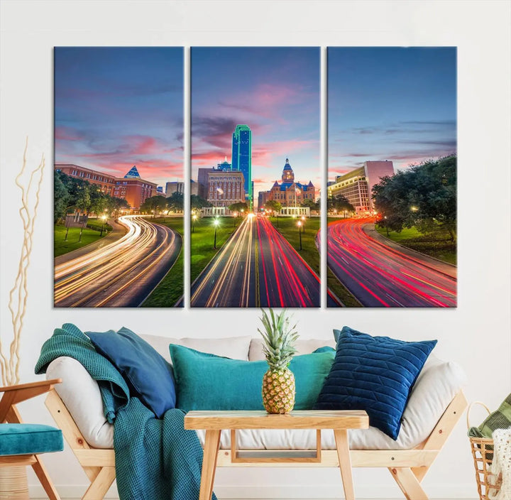 A modern living room features a cityscape triptych wall art titled "Dallas City Street Lights Sunset Pink Cloudy Skyline Cityscape View," printed on museum-quality canvas. It captures a vibrant evening skyline with light trails.