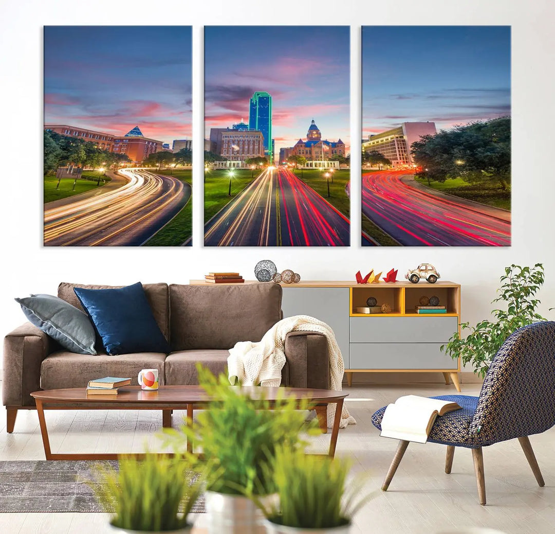 A modern living room features a cityscape triptych wall art titled "Dallas City Street Lights Sunset Pink Cloudy Skyline Cityscape View," printed on museum-quality canvas. It captures a vibrant evening skyline with light trails.