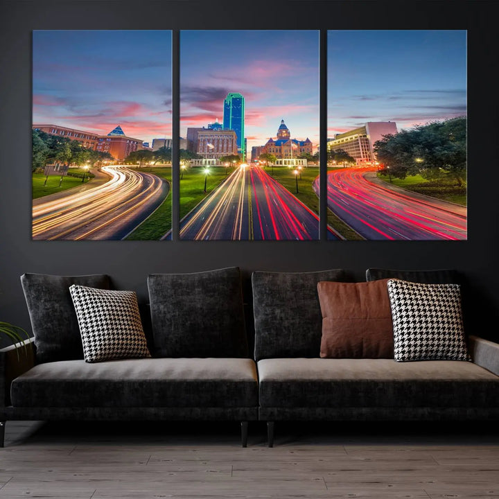 A modern living room features a cityscape triptych wall art titled "Dallas City Street Lights Sunset Pink Cloudy Skyline Cityscape View," printed on museum-quality canvas. It captures a vibrant evening skyline with light trails.