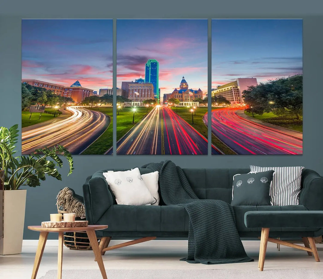 A modern living room features a cityscape triptych wall art titled "Dallas City Street Lights Sunset Pink Cloudy Skyline Cityscape View," printed on museum-quality canvas. It captures a vibrant evening skyline with light trails.