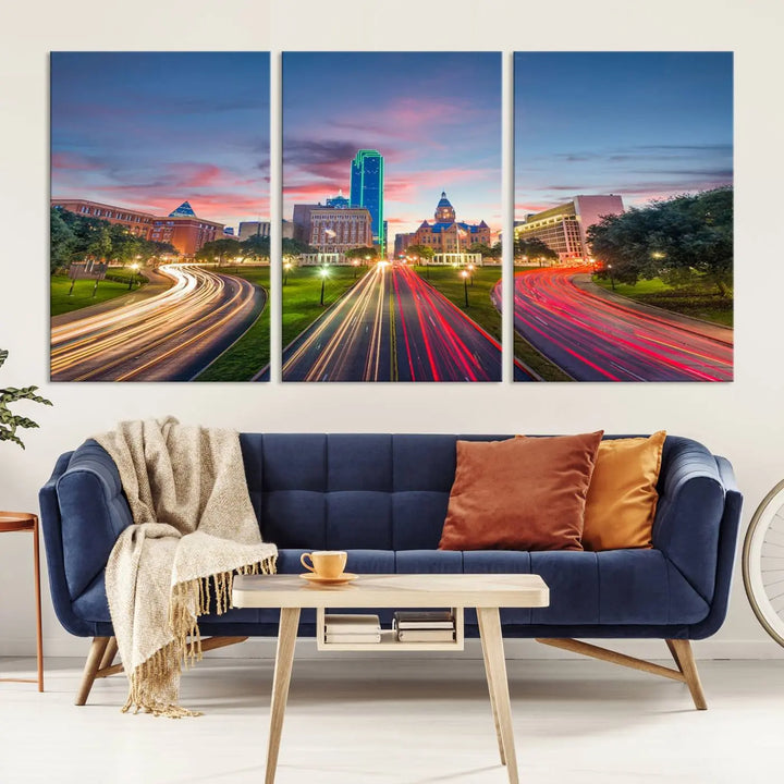 A modern living room features a cityscape triptych wall art titled "Dallas City Street Lights Sunset Pink Cloudy Skyline Cityscape View," printed on museum-quality canvas. It captures a vibrant evening skyline with light trails.