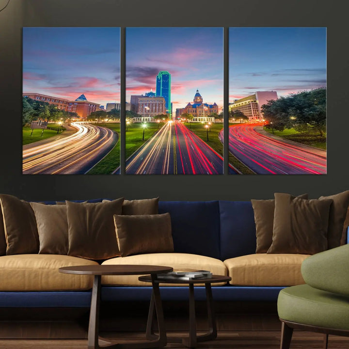 A modern living room features a cityscape triptych wall art titled "Dallas City Street Lights Sunset Pink Cloudy Skyline Cityscape View," printed on museum-quality canvas. It captures a vibrant evening skyline with light trails.